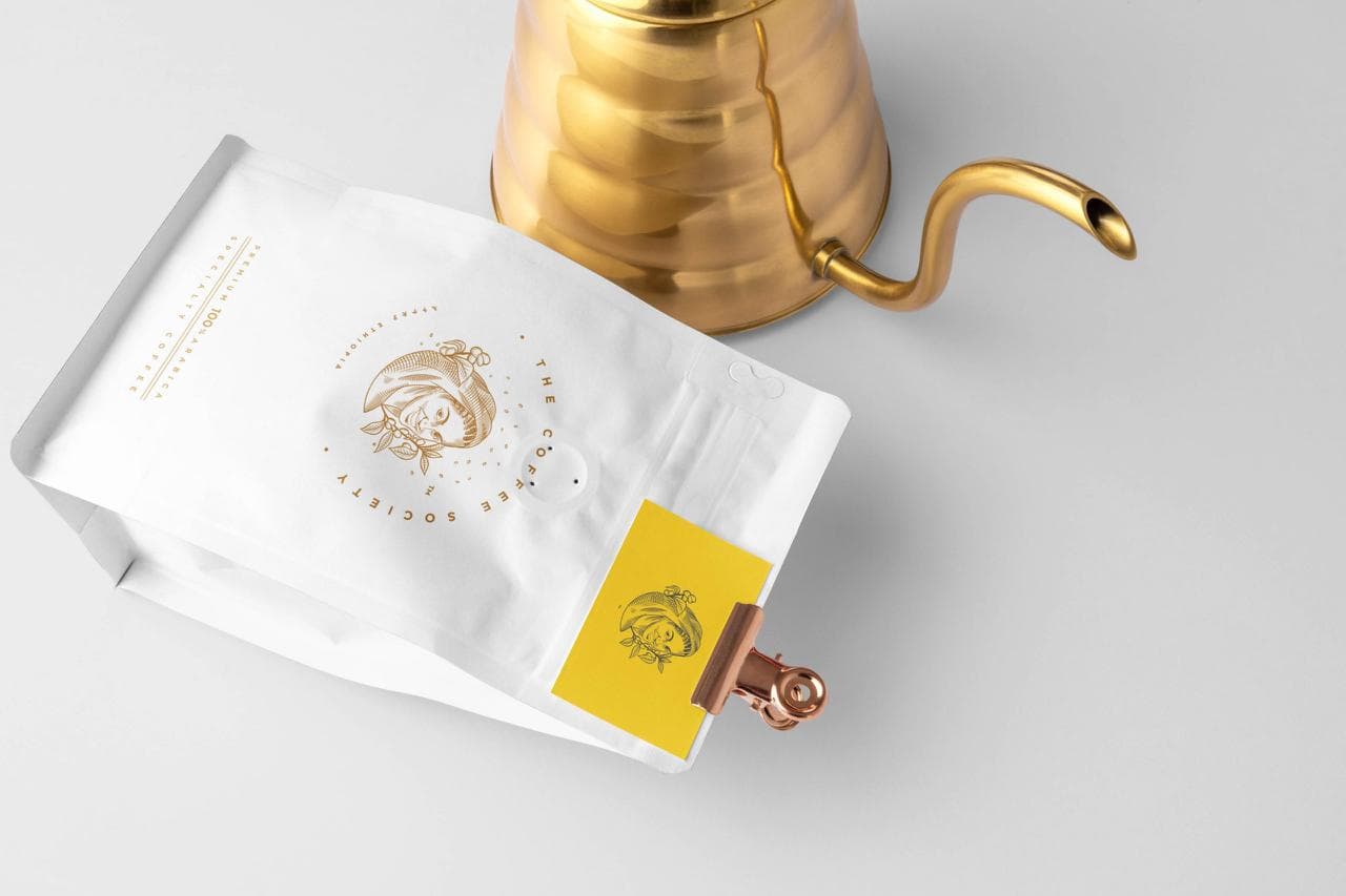 The signature white pouch, clipped, beside a gold pour-over kettle